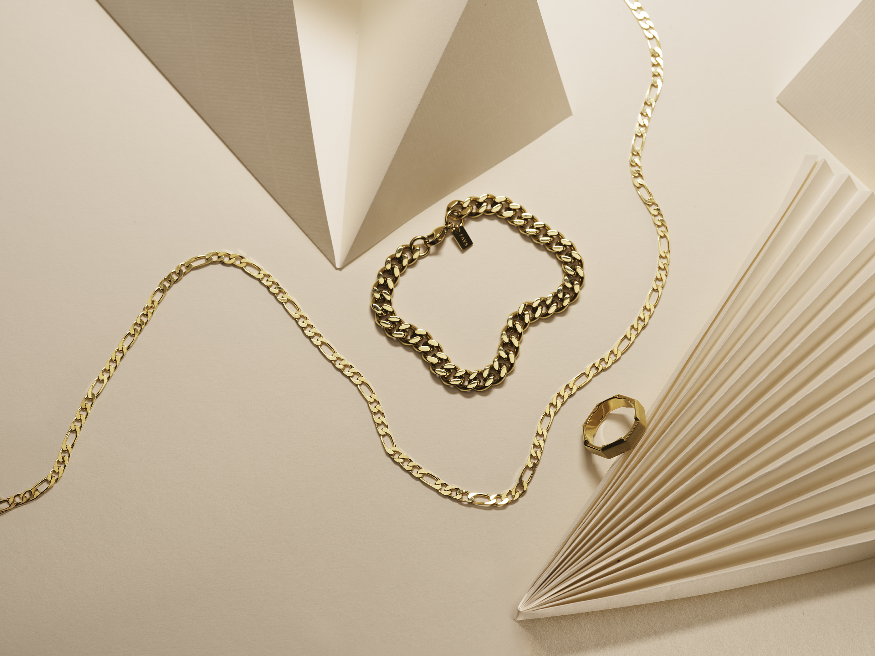 Link zu Herrenschmuck. Ein Armband, eine Kette und ein Ring in Gold.