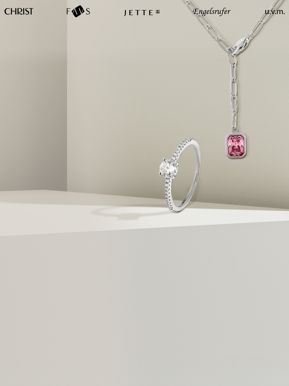 Kette und Ring vor beigem Hintergrund.