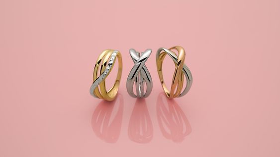 Drei Bicolor-Ringe in Gold und Silber mit verschlungenem Design.
