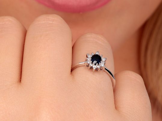 Ein Halo-Ring mit einem blauen Saphir an einer Hand
