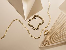 Lien vers des bijoux pour hommes. Un bracelet, une chaîne et une bague en or.