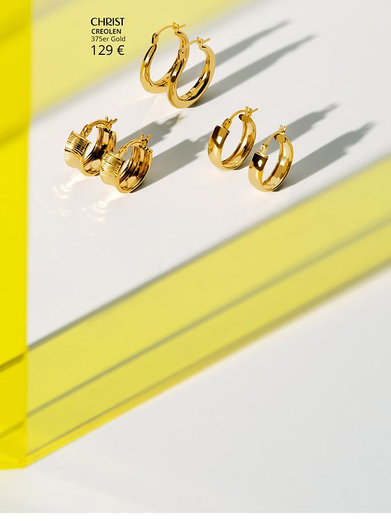 Goldene Creolen mit gelben Plexiglas Hintergrund.