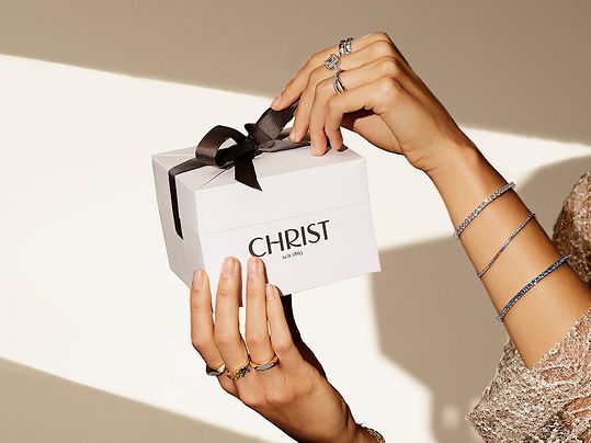 Frau hält die Geschenkverpackung von CHRIST hoch.