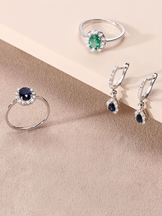 Zwei Ringe mit blauem Saphir und grünem Smaragd sowie ein Paar Ohrhänger mit dunkelblauen Edelsteinen und Diamantbesatz.