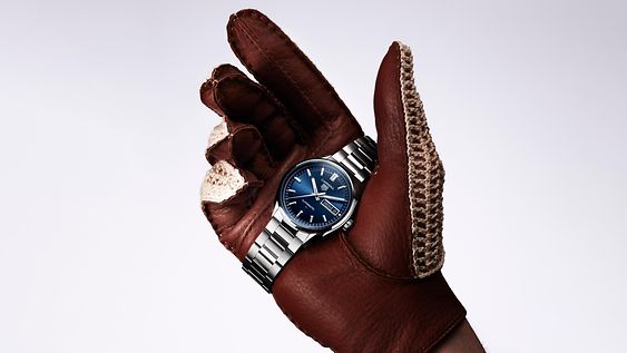 Eine Hand, die eine Tag Heuer mit blauem Ziffernblatt hält.