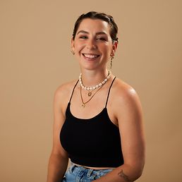 Portrait von Julia vor einem orangefarbenen Hintergrund.