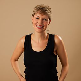 Portrait von Caro vor einem orangefarbenen Hintergrund.