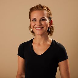 Portrait von Sarah vor einem orangefarbenen Hintergrund.