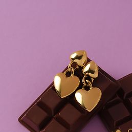 Goldene GMK Ohrstecker in Herzform auf lila Hintergrund.