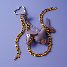 Eine GMK Kette auf lila Hintergrund neben einem Dackelschlüsselanhänger.