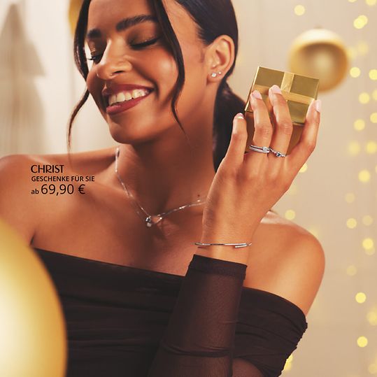 Weibliches Model mit Diamantschmuck und goldenem Geschenk.