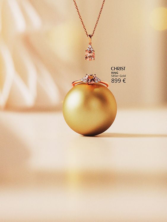 Farbsteinring und Kette vor goldenem Hintergrund.