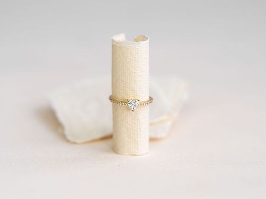 Zarter Goldring mit Diamanten auf einer cremefarbenen Schmuckrolle.