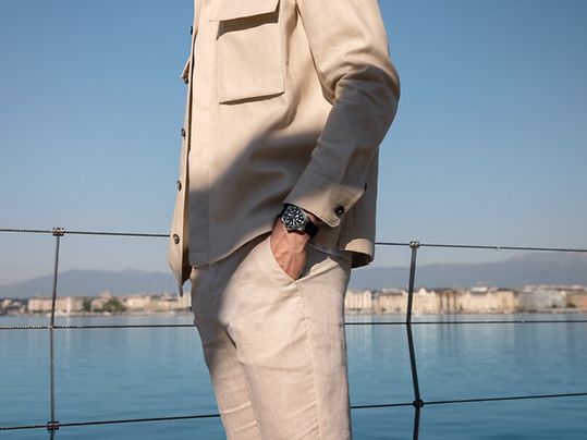 Mann in einem hellen Anzug mit einer TUDOR Pelagos am Handgelenk an einer Meeresbucht