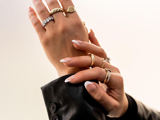 Zwei Hände einer Frau, die nach oben gehalten werden, geschmückt mit mehreren Ringen