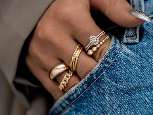 Eine mit vielen Ringen geschmückte Hand, die lässig in der Tasche einer Jeanshose steckt