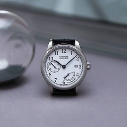 Eine Uhr von Union Glashütte mit einer Sanduhr im Hintergrund.